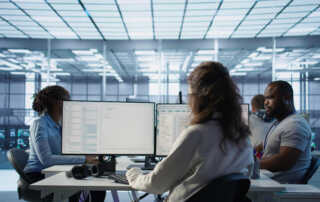 Duas mulheres e branca e um homem preto sentadas trabalhando em notebooks.
