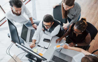 Grupo de pessoas debatendo à frente de um notebook